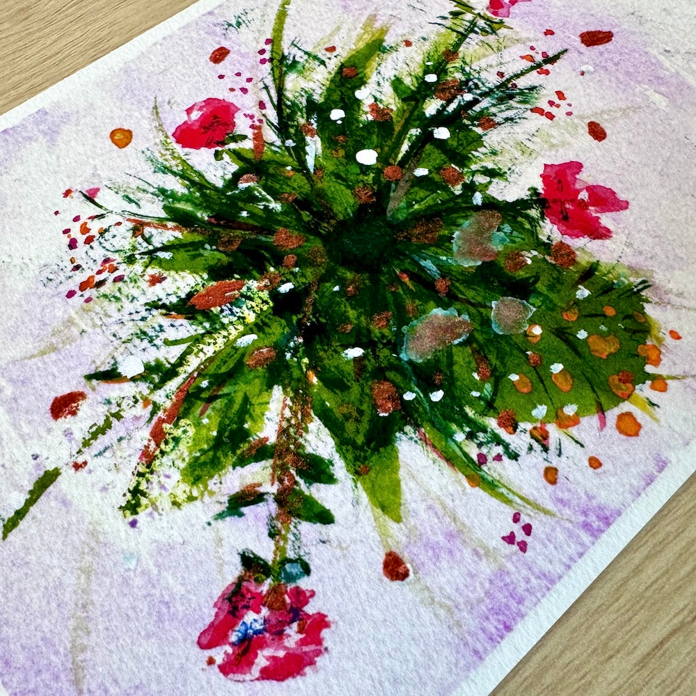 Gros plan d’une illustration aquarelle représentant un bouquet vu du dessus, composé de feuillage vert vif et de fleurs rouges et roses. La texture du papier est visible, mettant en valeur les détails de la peinture et les éclaboussures de couleurs sur un fond rose clair. Appartient à Boutique de Moments.