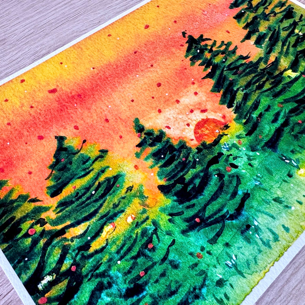 Gros plan d’une illustration aquarelle montrant une forêt de sapins sous un ciel orange intense au coucher du soleil. Les détails de la texture du papier accentuent les contrastes entre les verts profonds des arbres et les teintes chaudes du ciel, créant une ambiance chaleureuse et apaisante. Appartient à Boutique de Moments.