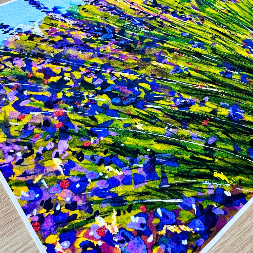 Gros plan d’une illustration aquarelle représentant un champ de lavande. Les nuances de violet, bleu et vert se mêlent dans une composition vibrante, mettant en valeur la texture du papier et la richesse des couleurs. Appartient à Boutique de Moments.