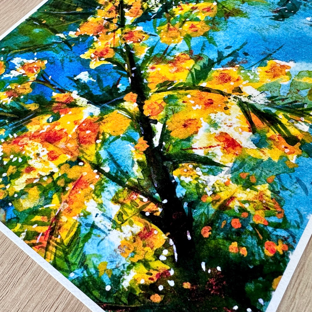 Gros plan d’une illustration aquarelle montrant des branches de mimosa en fleurs, aux teintes jaunes éclatantes, contrastant avec un ciel bleu vif. La texture du papier met en valeur les détails lumineux et les éclaboussures de couleur, évoquant une ambiance chaleureuse et ensoleillée. Appartient à Boutique de Moments.