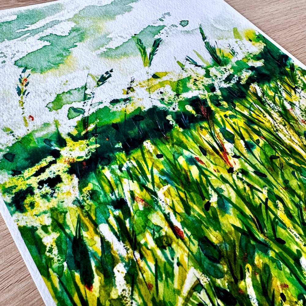 Gros plan d’une aquarelle représentant des herbes sauvages vertes et lumineuses sous un ciel nuageux, avec des détails de textures et de nuances de vert mettant en valeur la fraîcheur et la vitalité du paysage naturel. Appartient à Boutique de Moments.