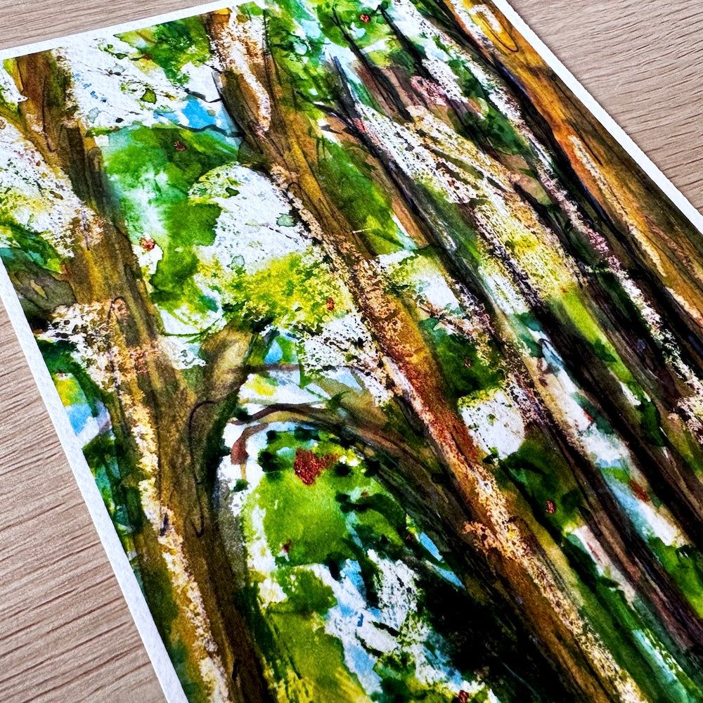 Gros plan sur une illustration à l’aquarelle de troncs d’arbres majestueux et feuillage verdoyant, baignée de lumière naturelle. Appartient à Boutique de Moments.